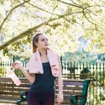 woman stands on a bench holding a towel, smiling as she enjoys the outdoors