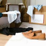 A cluttered room with cardboard boxes labelled "Keep," "Don't," and "Trash" filled with clothes